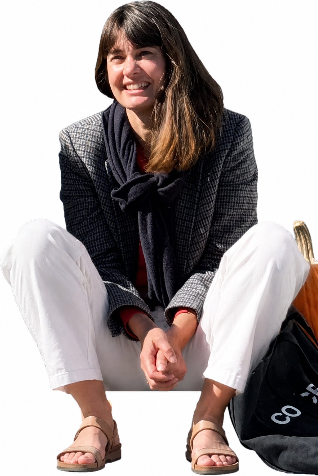 Smiling woman with a pumpkin sitting on sunlit porch steps
