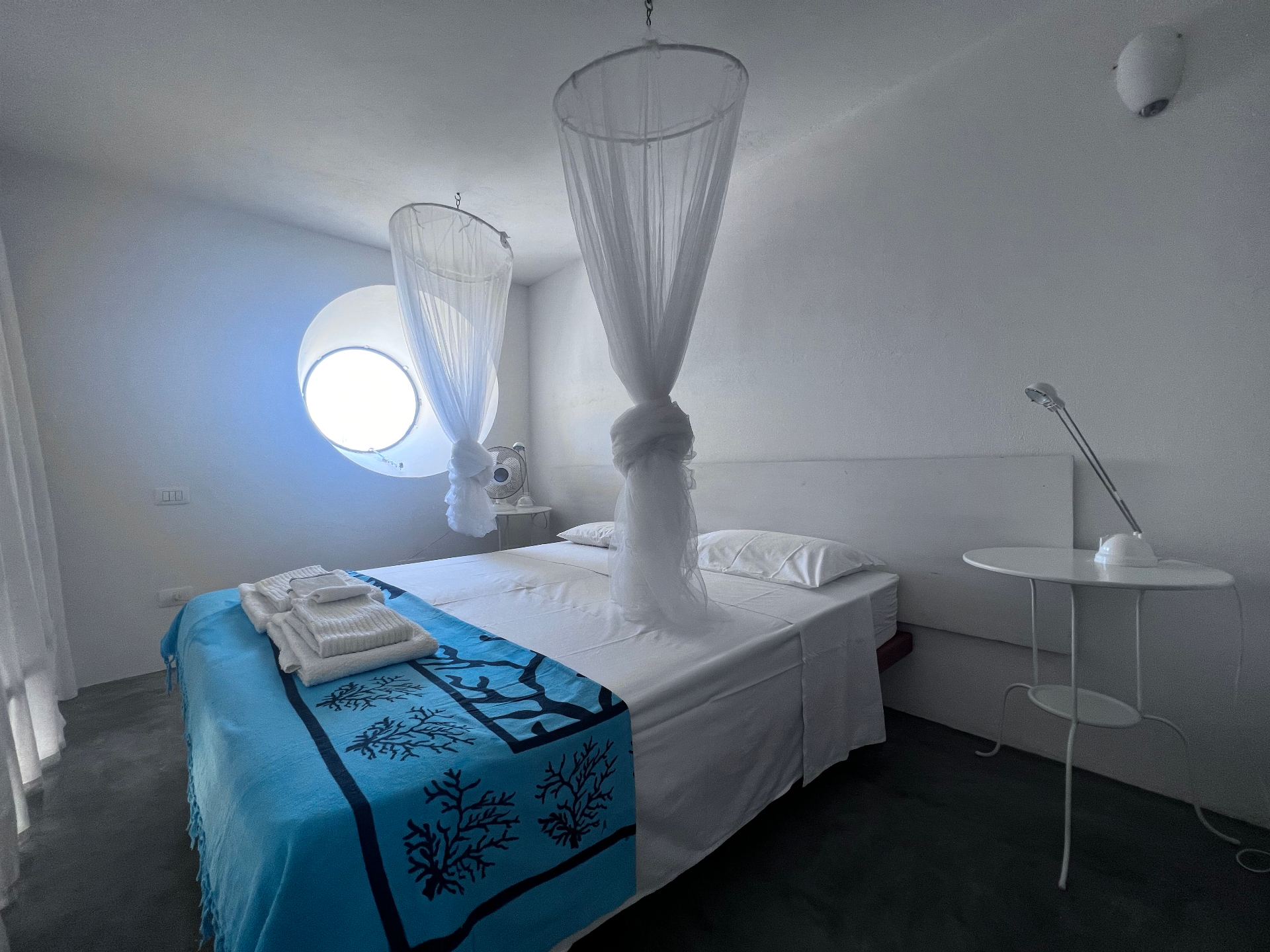 Safari Room with twin beds, coral-print turquoise throw, mosquito net canopies, and round porthole window