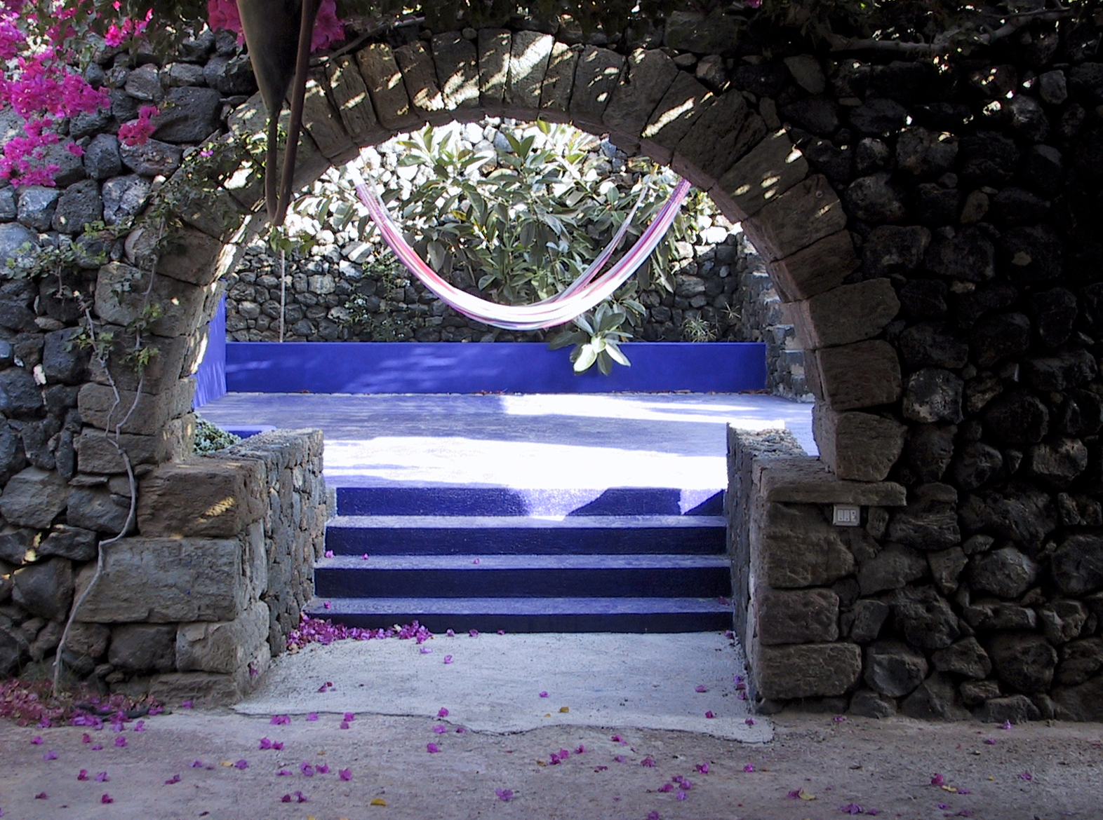 View through a stone arch into the Blue Patio with colorful hammocks strung between walls