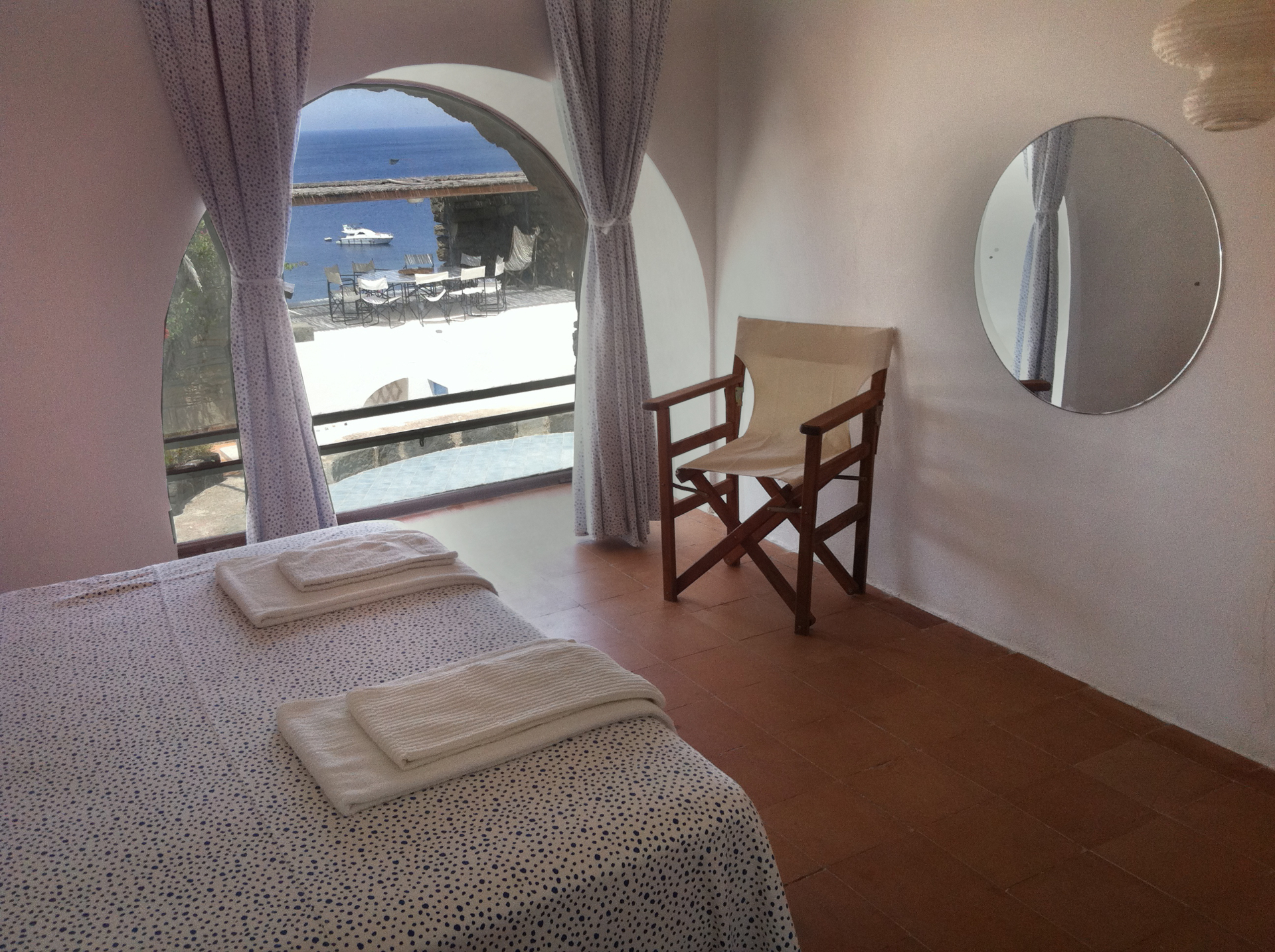 Royal Suite with arched window framing sea view, moored boat, and director's chair