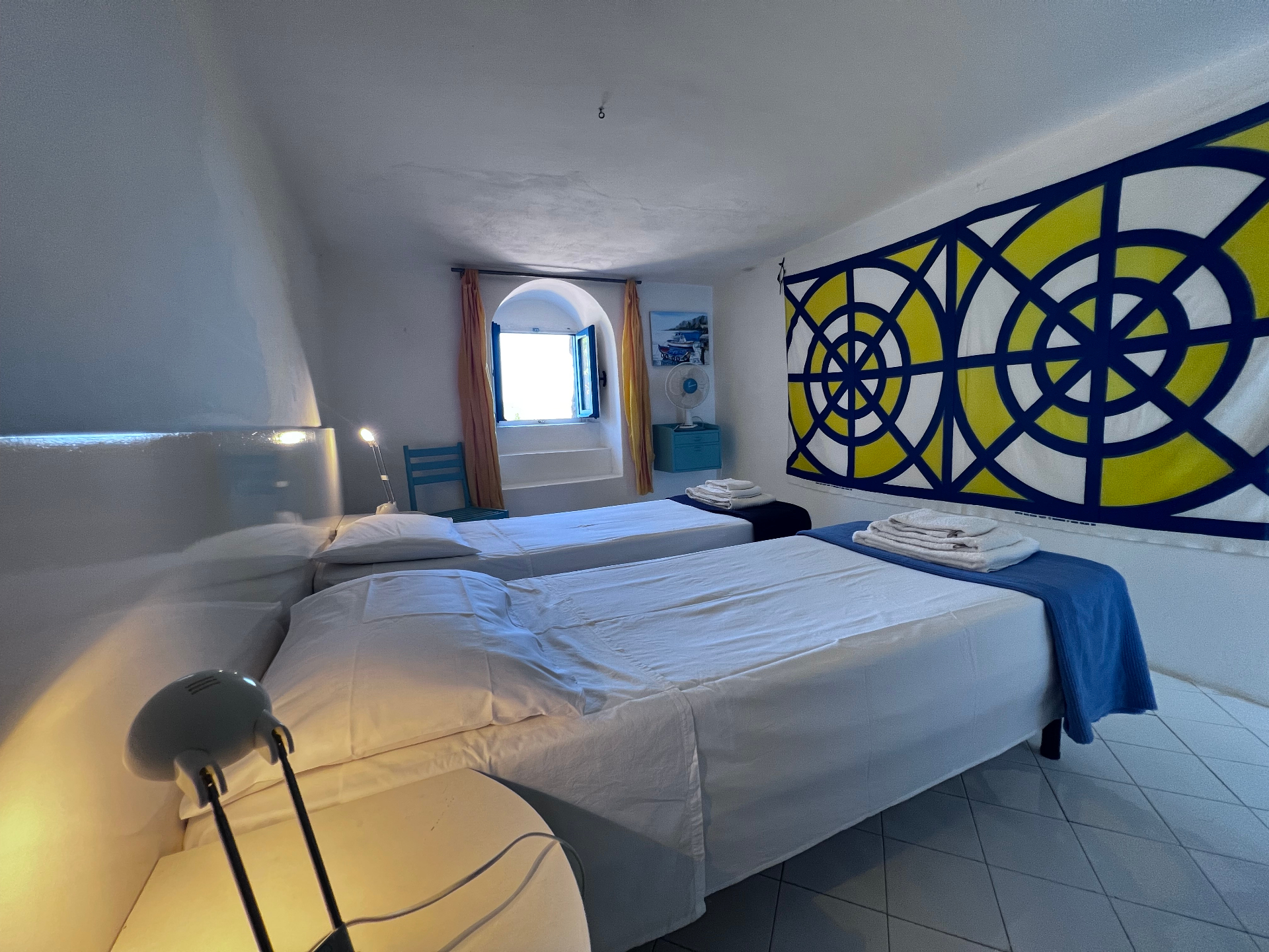 The Atlantic cabin — western room with twin beds, yellow and blue geometric tapestry, and arched window