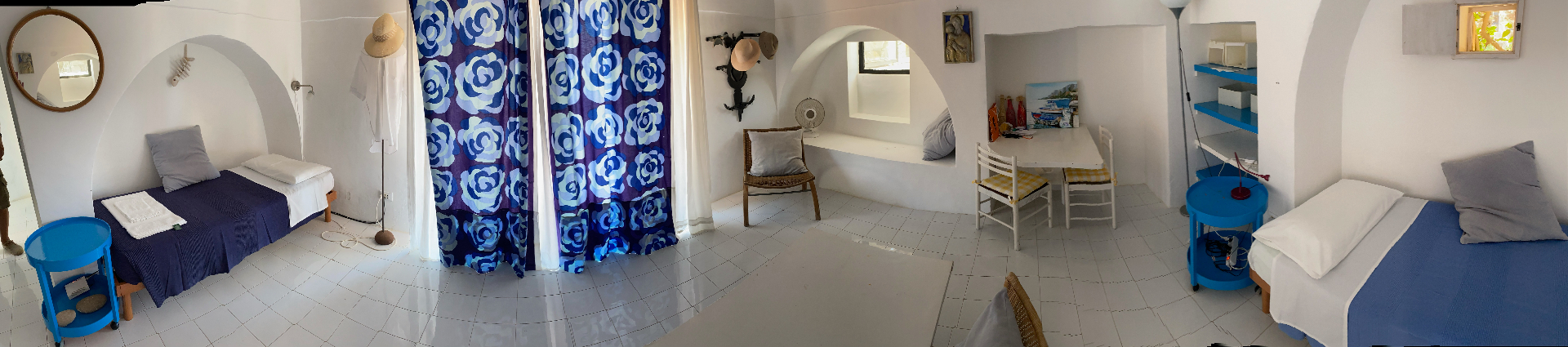Wide panoramic view of the Stonehouse interior with twin beds, blue rose curtains and arched alcoves
